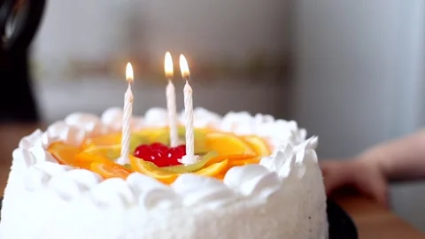 Little cute boy blowing three candles on tasty big cake with fresh fruits. Happy Stockbeeldmateriaal 130964799