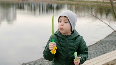 Little cute boy with bubbles by the river, outdoors Stockbeeldmateriaal 106871282