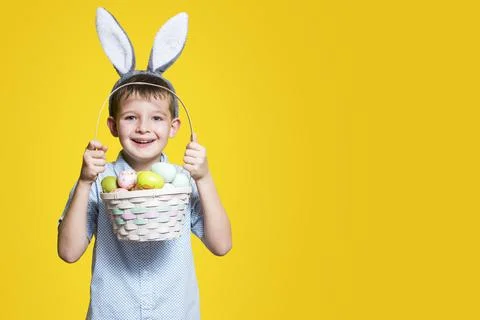 Little cute boy with an Easter basket in his hands and bunny ears on his head Stock Photos