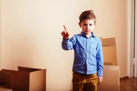 Little cute boy in empty room, move to new house. home alone among boxes close Stock Photos