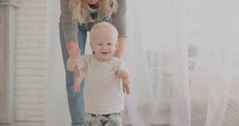 Little cute boy making his first steps under control of mother. kid happily 動画素材 92005202
