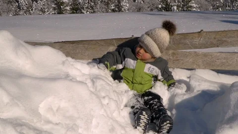 Little cute boy playing in the snow outside in winter. In the background is a Stock Footage 100589752