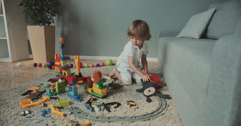 Little cute boy sitting on the floor and enjoying toys at home. Baby designer Stock Footage 80997993
