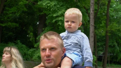 Little cute boy sitting on his father's neck in park Father's day Stock Footage 90258459