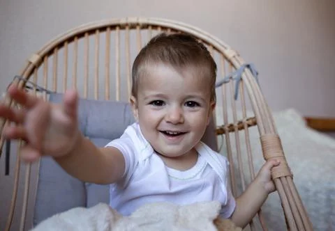 Little cute boy smiling while sitting in a chair in the bedroom Stock Photos