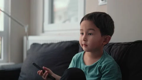Little cute boy switch channels with remote control on TV at home Stock Footage 187050696