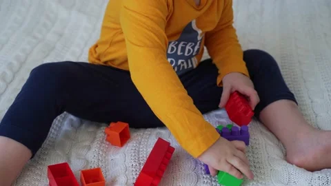 Little cute boy of two years old plays children's constructor sitting on the bed Stock Footage 169543715