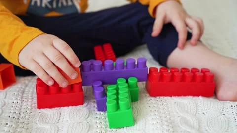 Little cute boy of two years old plays children's constructor sitting on the bed Stock Footage 169543837