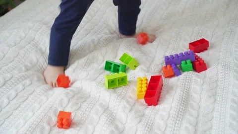 Little cute boy of two years old plays children's constructor sitting on the bed Stock Footage 169544152