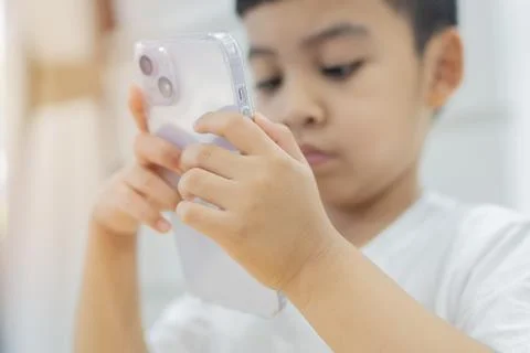 Little cute boy in a white T-shirt playing games on a phone and watching ca.. Foto stock