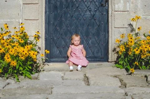 Little cute girl in pink dress at a castle yard. Stock Photos