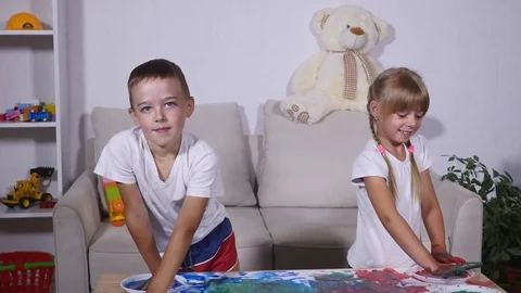 A little cute happy funny child painting color handprints on the white sheet of Stock Footage