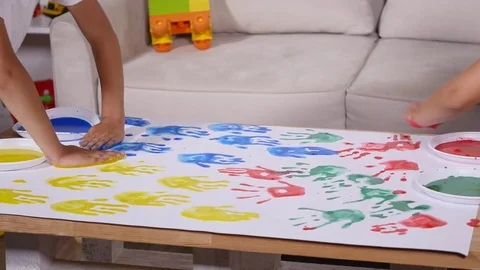 A little cute happy funny child painting color handprints on the white sheet of Stock Footage