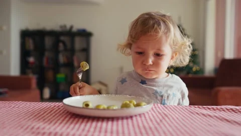Little cute kid with appetite eats olives itself with fork Video stock 229778934