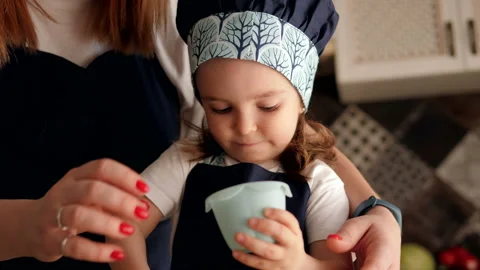 Little cute three-year-old girl puts the dough in a baking dish, mom helps her. Stock Footage 120841825