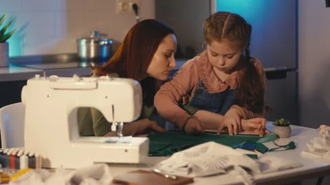 Little daughter drafting pattern before cutting fabric, sewing activity with mom Video stock 310949849
