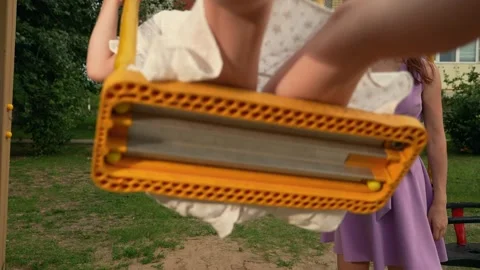 Little daughter waves hand to camera playing swings with mother on playground Stock Footage 253121043