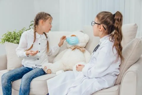 Little doctor prescribed pills for ill teddy bear and is explaining how to take Stock Photos