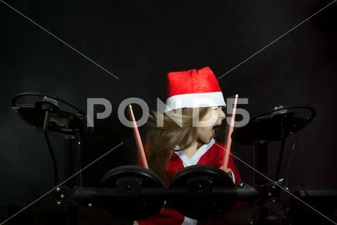 Little drummer disguised as Santa Claus playing the elettronic drum kit Stock Photos