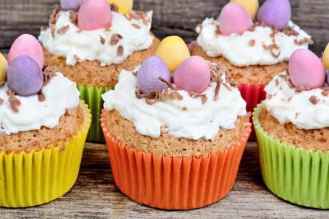 Little easter cupcakes with easter eggs and frosting on wood background Stock Photos