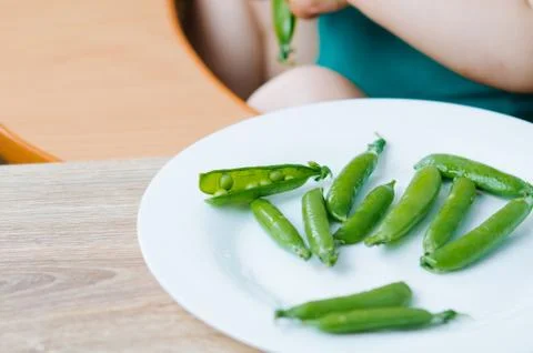 Little eats peas in the kitchen Stock Photos
