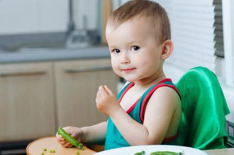 Little eats peas in the kitchen Stock Photos