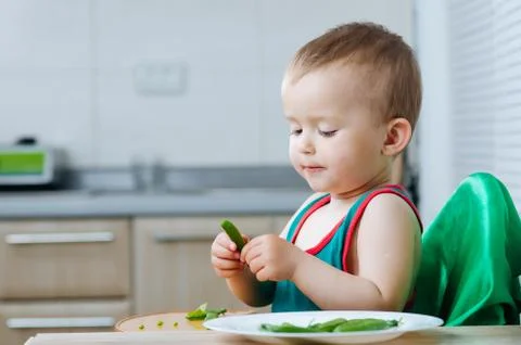 Little eats peas in the kitchen Stock Photos