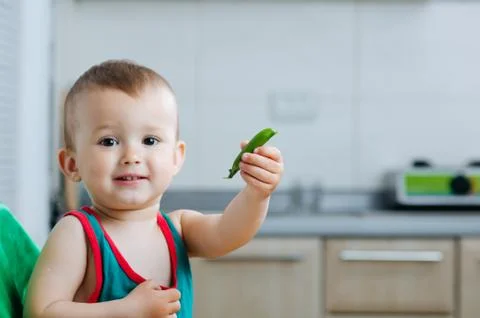 Little eats peas in the kitchen Stock Photos