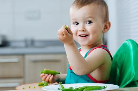 Little eats peas in the kitchen Stock Photos