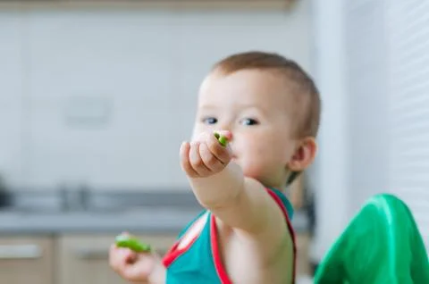 Little eats peas in the kitchen Stock Photos