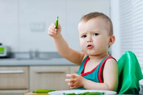 Little eats peas in the kitchen Stock Photos
