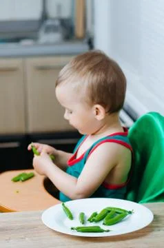 Little eats peas in the kitchen Stock Photos