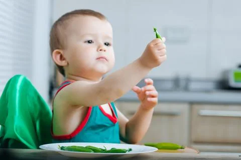 Little eats peas in the kitchen Stock Photos