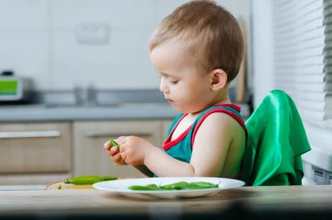 Little eats peas in the kitchen Stock Photos