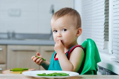 Little eats peas in the kitchen Foto stock