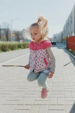 A little European girl jumps in the city on a summer day. incredibly emotiona Stock Photos