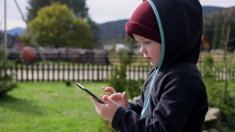 Little excited boy using smartphone mobile looking photos tapping touchscreen 動画素材 165113374