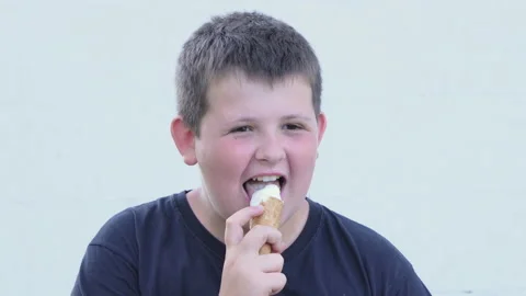 Little fat boy eats ice cream on the street. Satisfied facial expression. Stock Footage 197571082