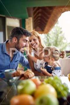 Little female feeds father with grape. Stock Photos