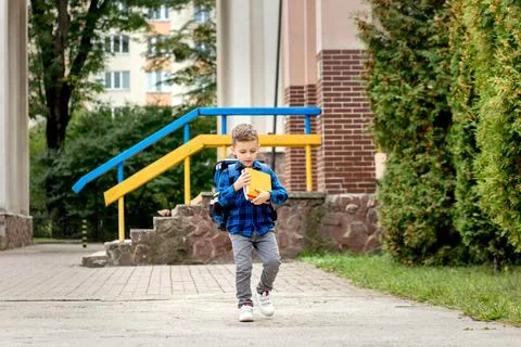Little first grader with backpack looking the copybook, going home from schoo Stock Photos