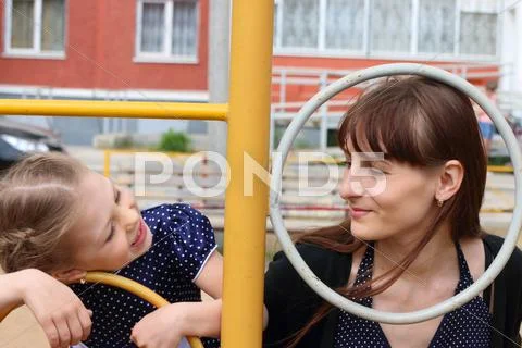 Little girl and her mother plays on children playground Stock Photos
