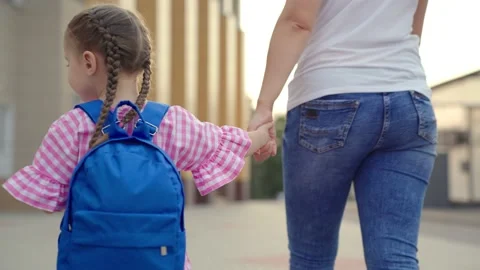 Little girl with backpack holds her mother by the hand and goes to school, kid Stock Footage