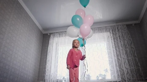 Little girl with blond hair, dressed in a pink blouse and pants jumping on the Stock Footage