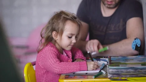 Little girl with blond hair, dressed in a children's blouse, is engaged in Stock Footage
