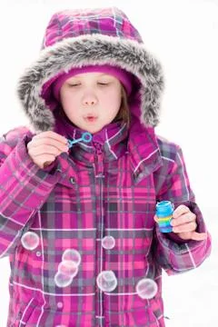 Little girl blowing bubbles in snow Stock Photos