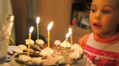 Little girl blowing out candles on cake Stock Footage