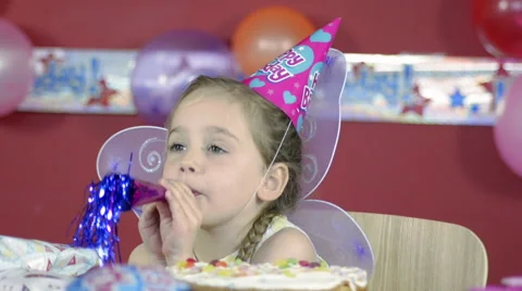 Little Girl Blows into a Noisemaker on her Birthday Stock Footage