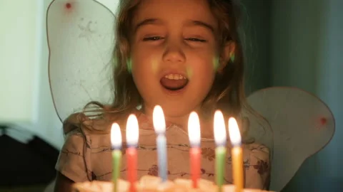 Little girl blows out candles on birthday cake at party. Closeup. Slow motion Stock Footage
