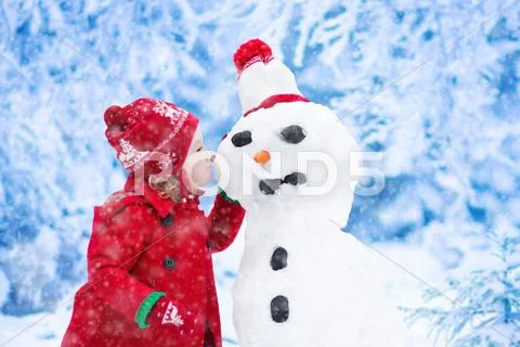 Little girl building snow man in winter Stock Photos
