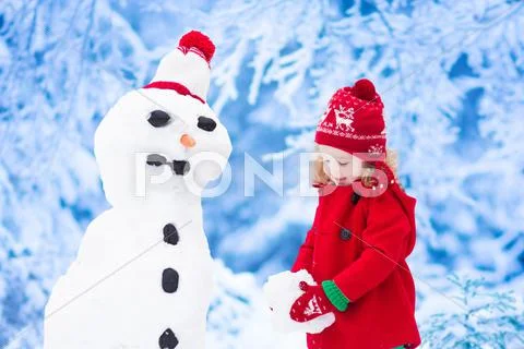 Little girl building a snow man in winter Stock Photos